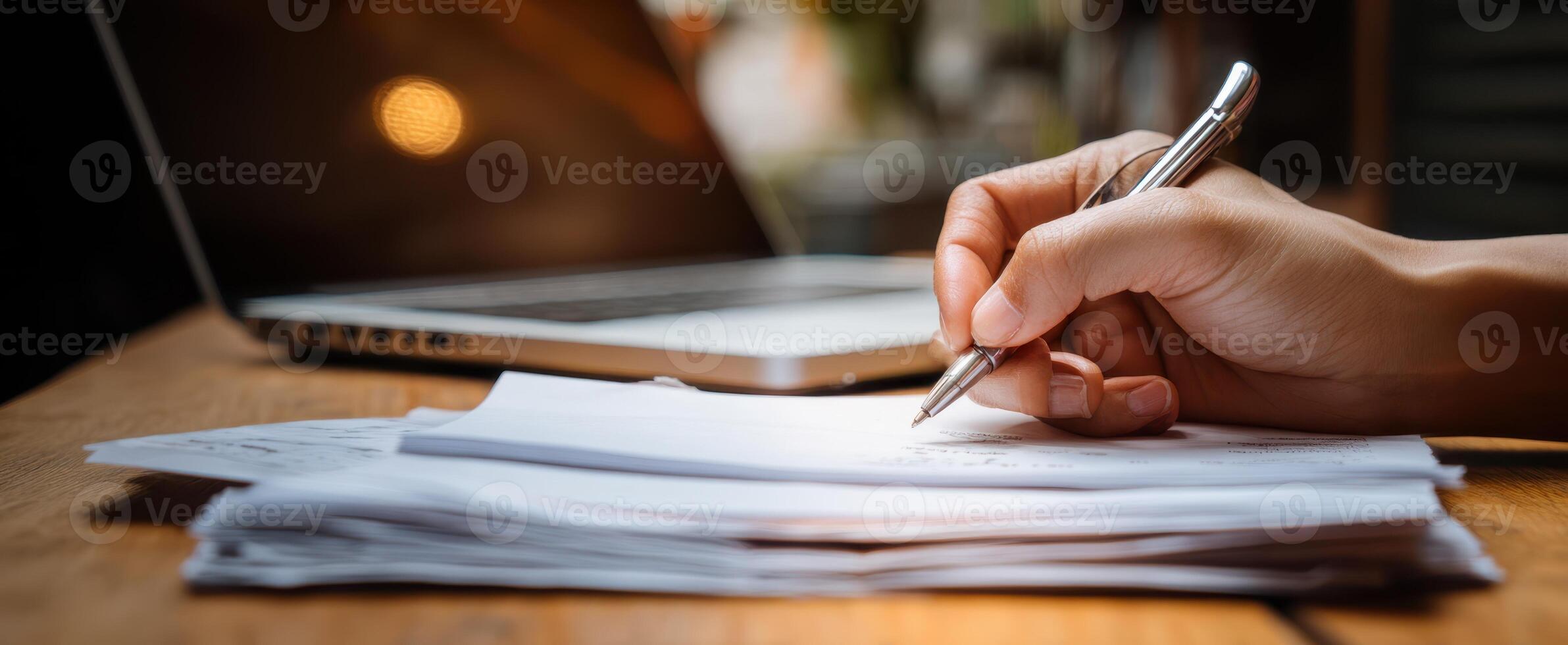The hand writing on documents with a laptop in a modern workspace. photo