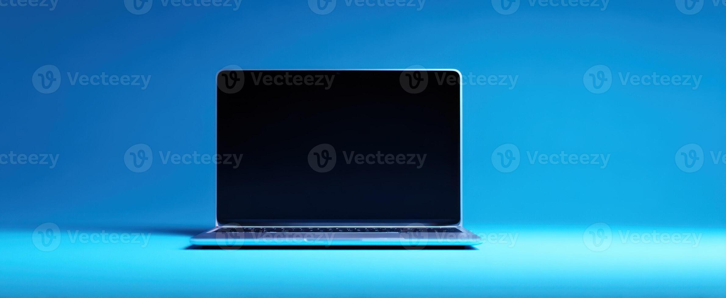 The sleek laptop with a blank screen on a vibrant blue background. photo