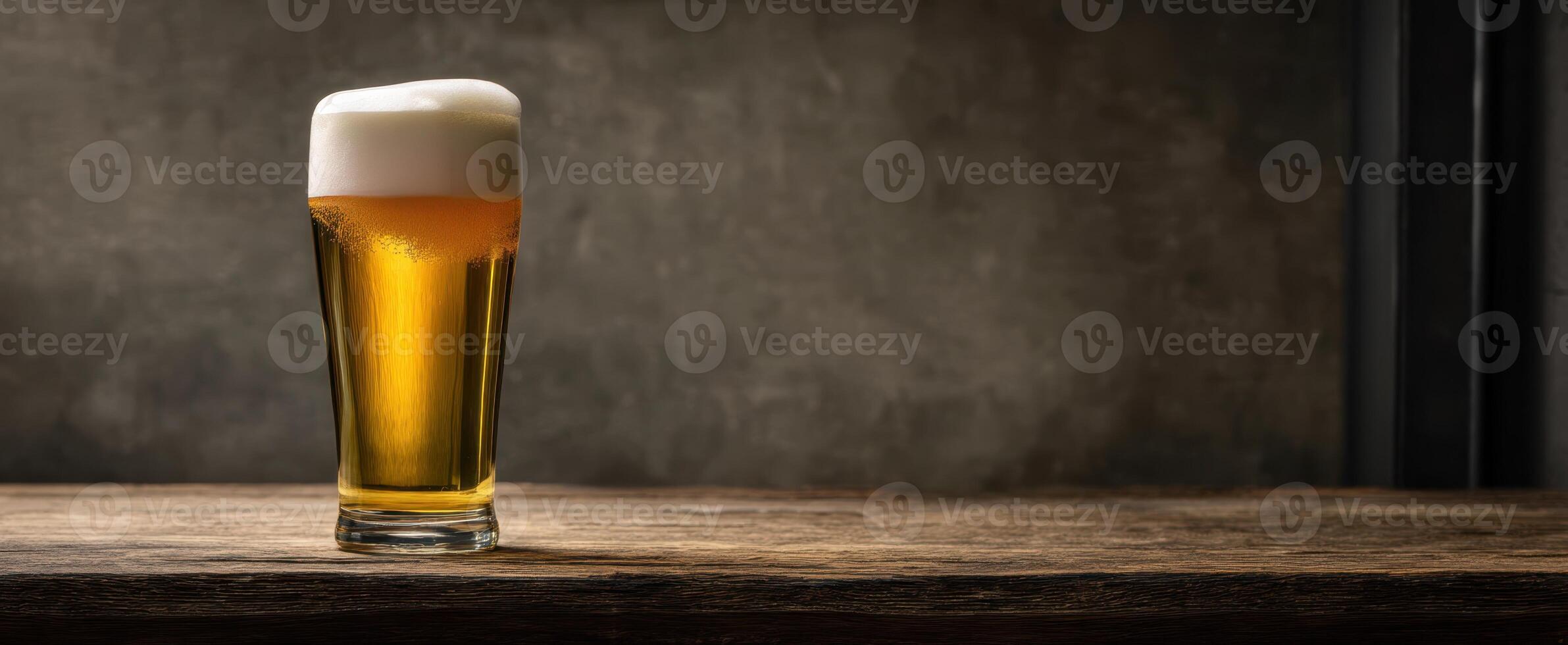 The refreshing glass of golden beer with creamy foam on a rustic table. photo