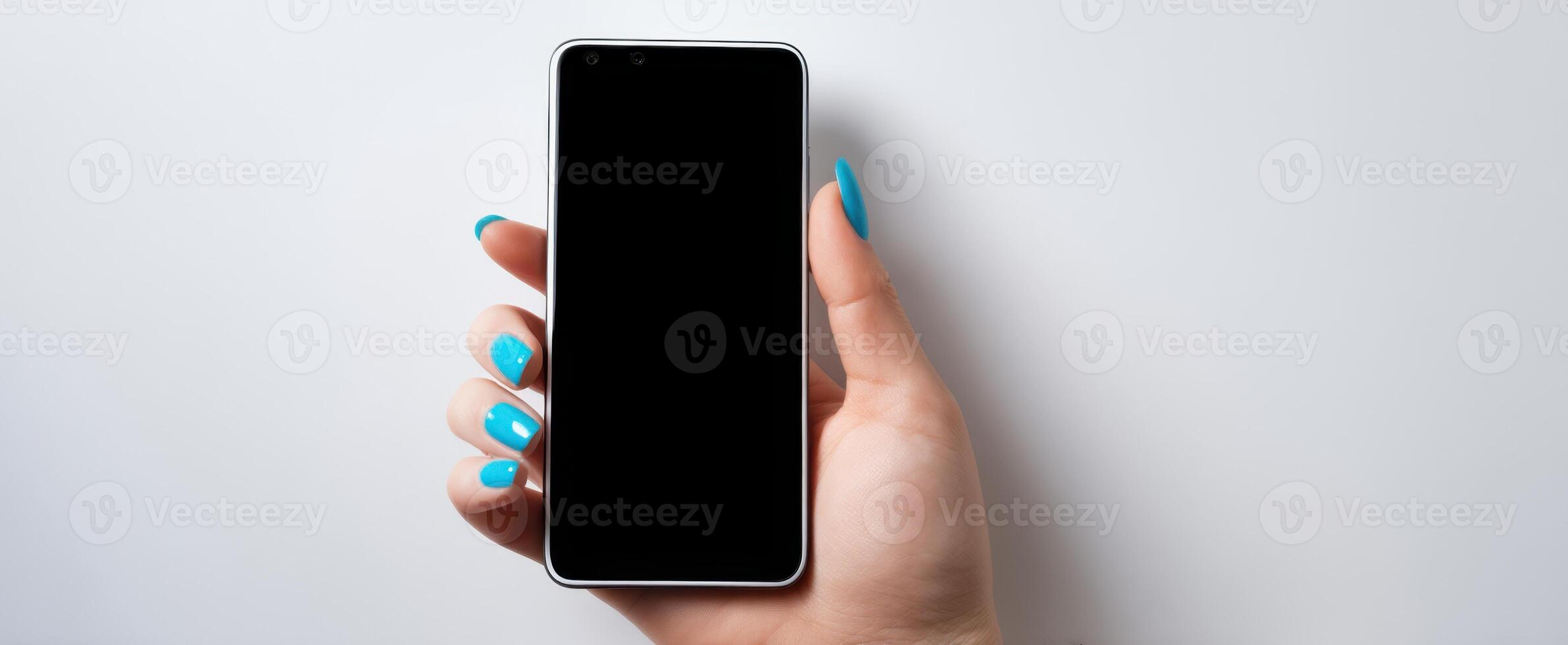 The smartphone held by a hand with stylish blue nails on a minimal backdrop. photo