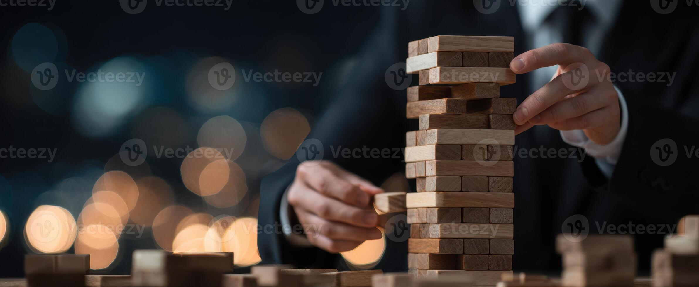 The businessman skillfully builds a wooden block tower amidst evening lights. photo
