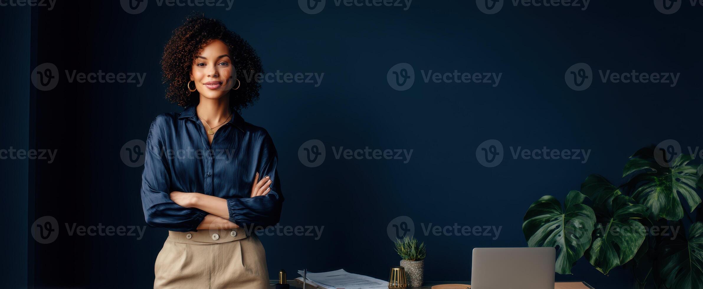 The confident woman standing in a modern office space with a laptop. photo
