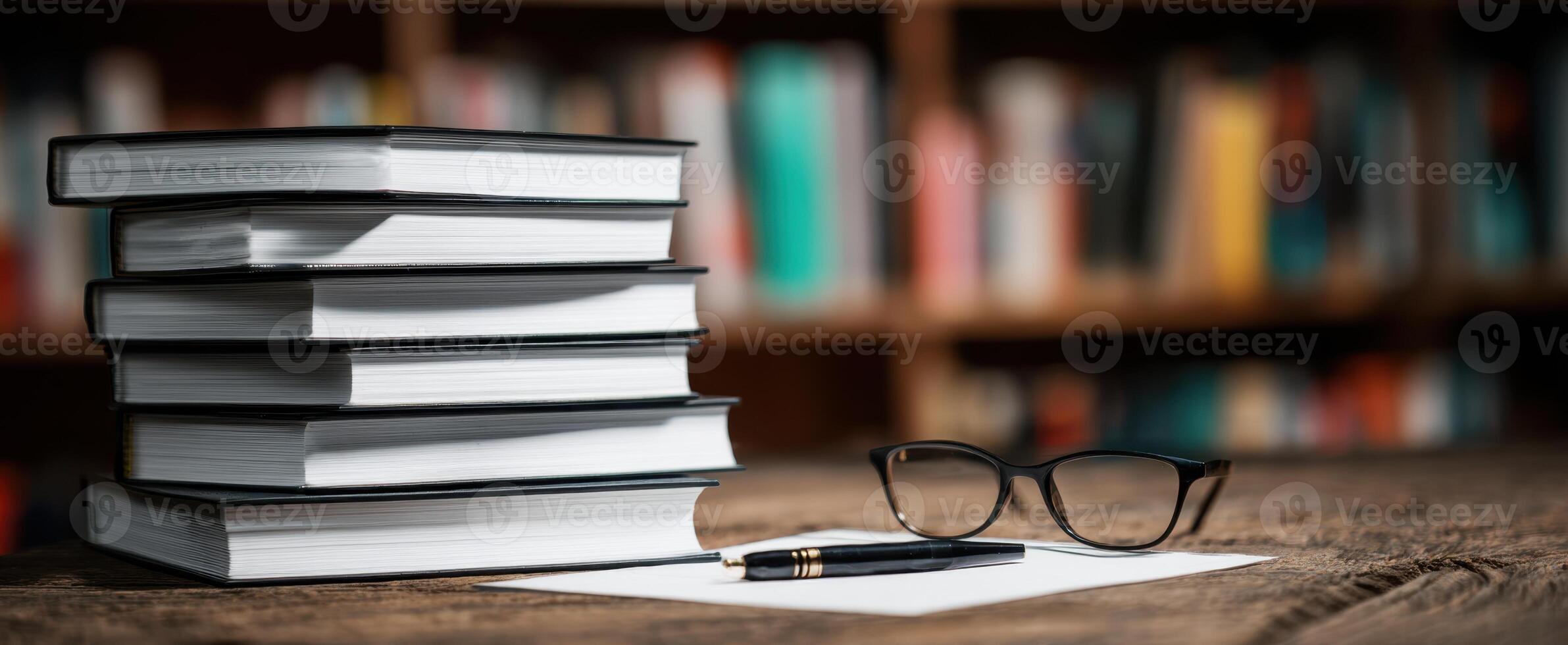 The stacked books and stationery on a wooden desk in a cozy library setting. photo
