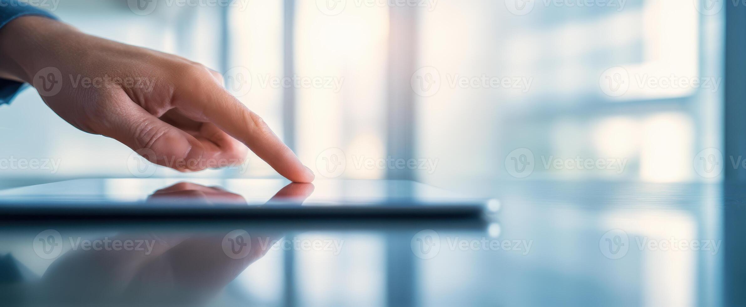 The hand interacting with a sleek tablet in a modern office environment photo