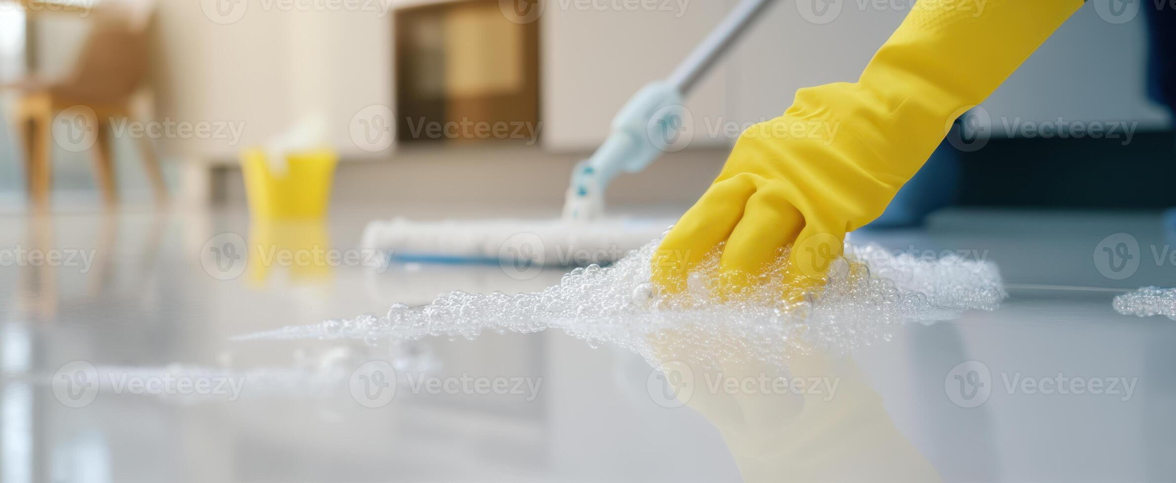 The cleaning process with soap bubbles and yellow gloves on a shiny floor. photo