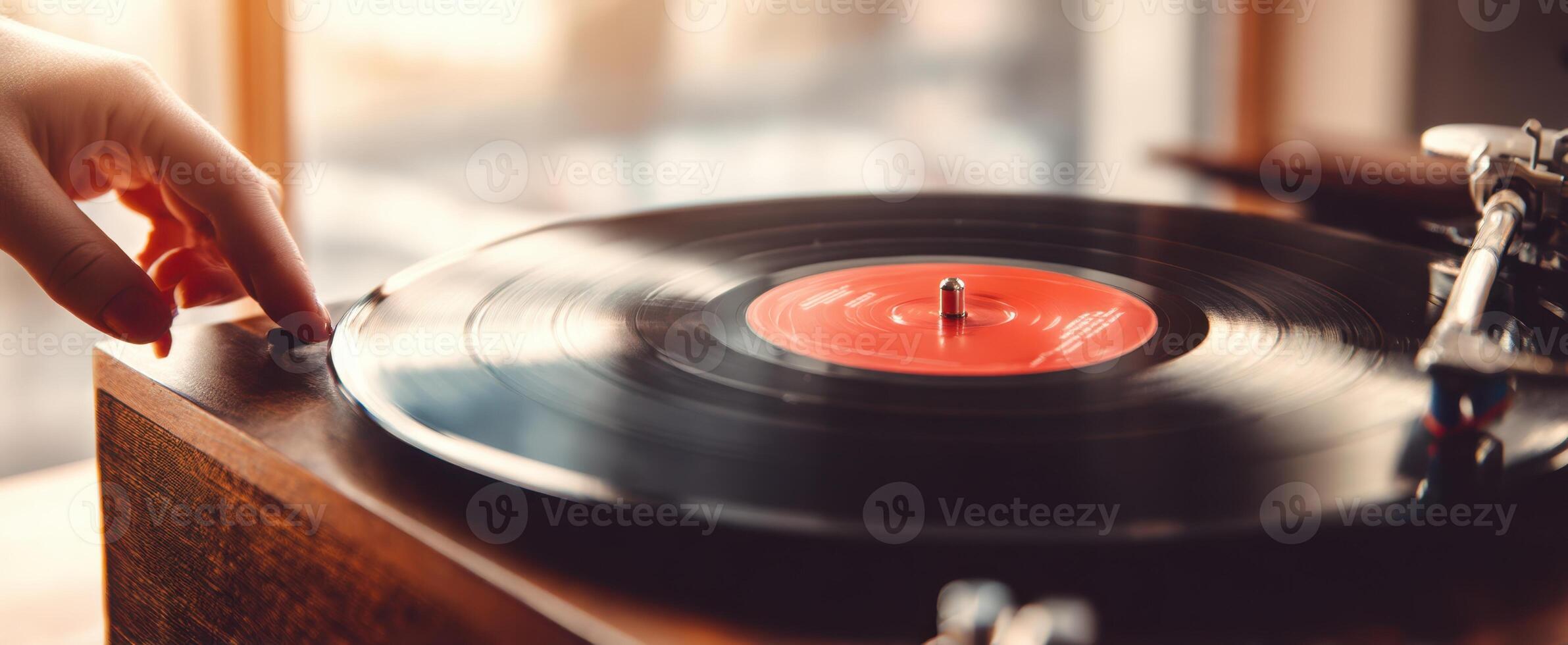 The hand reaching for a spinning vinyl record on a turntable. photo