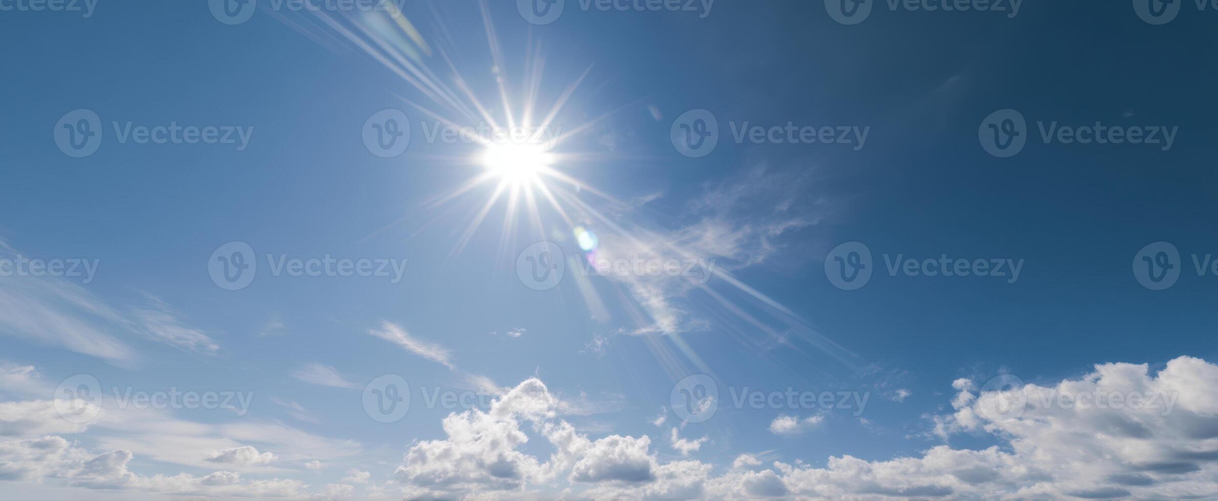 The radiant sun shining over a clear blue sky with fluffy clouds. photo