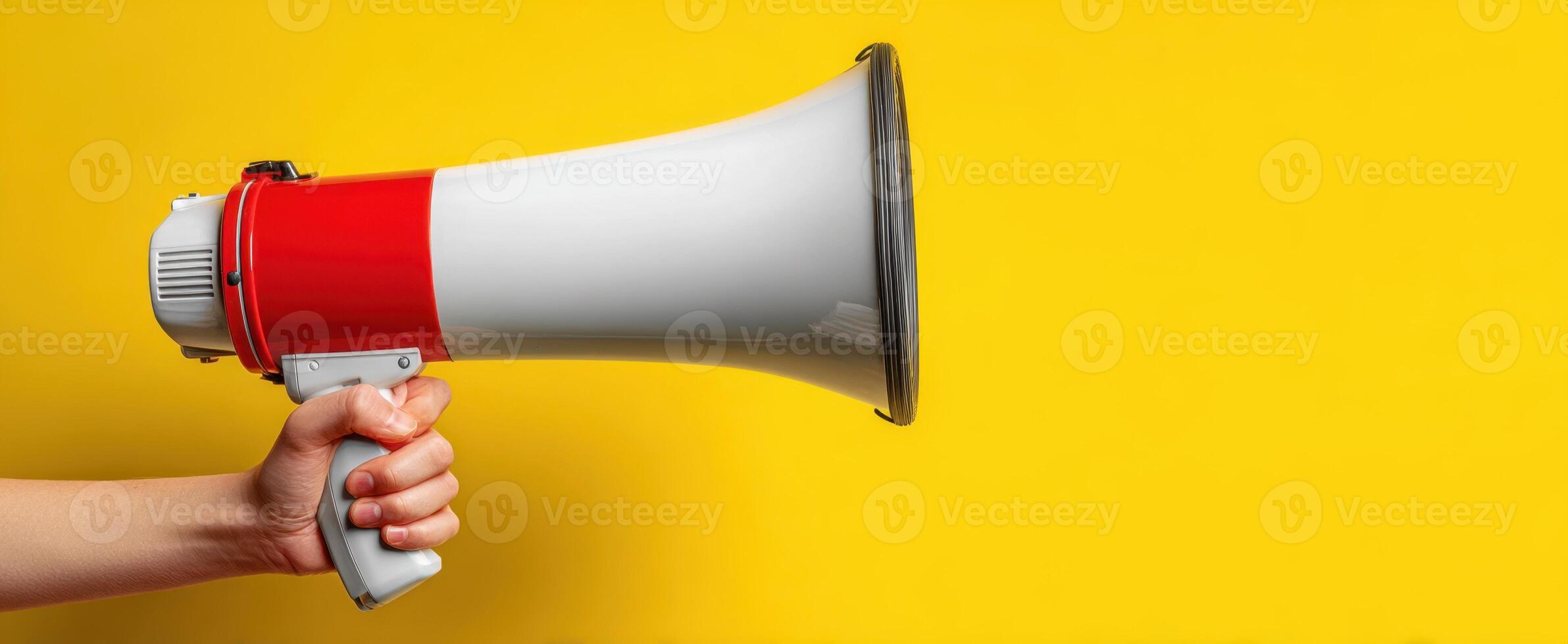 The megaphone held against a vibrant yellow background for effective communication. photo