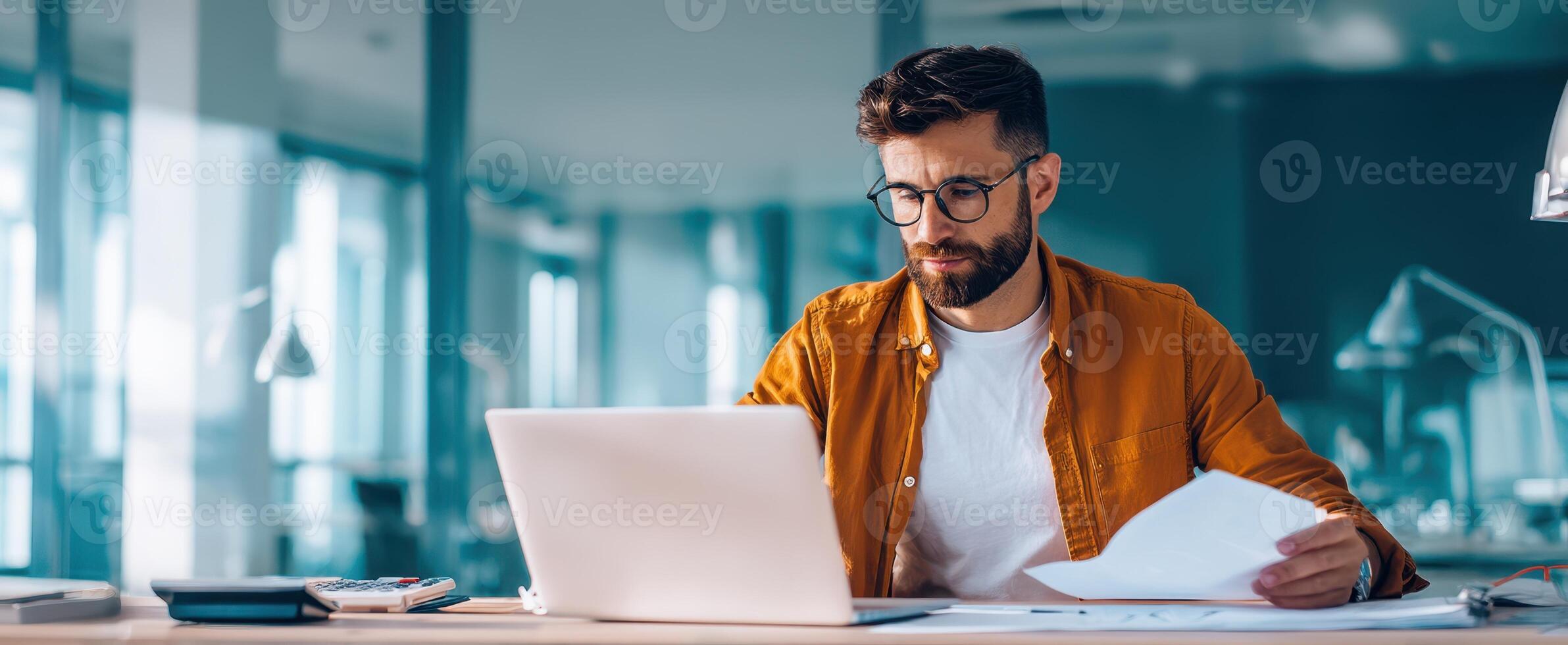 The focused businessman analyzing documents at a modern office workspace. photo