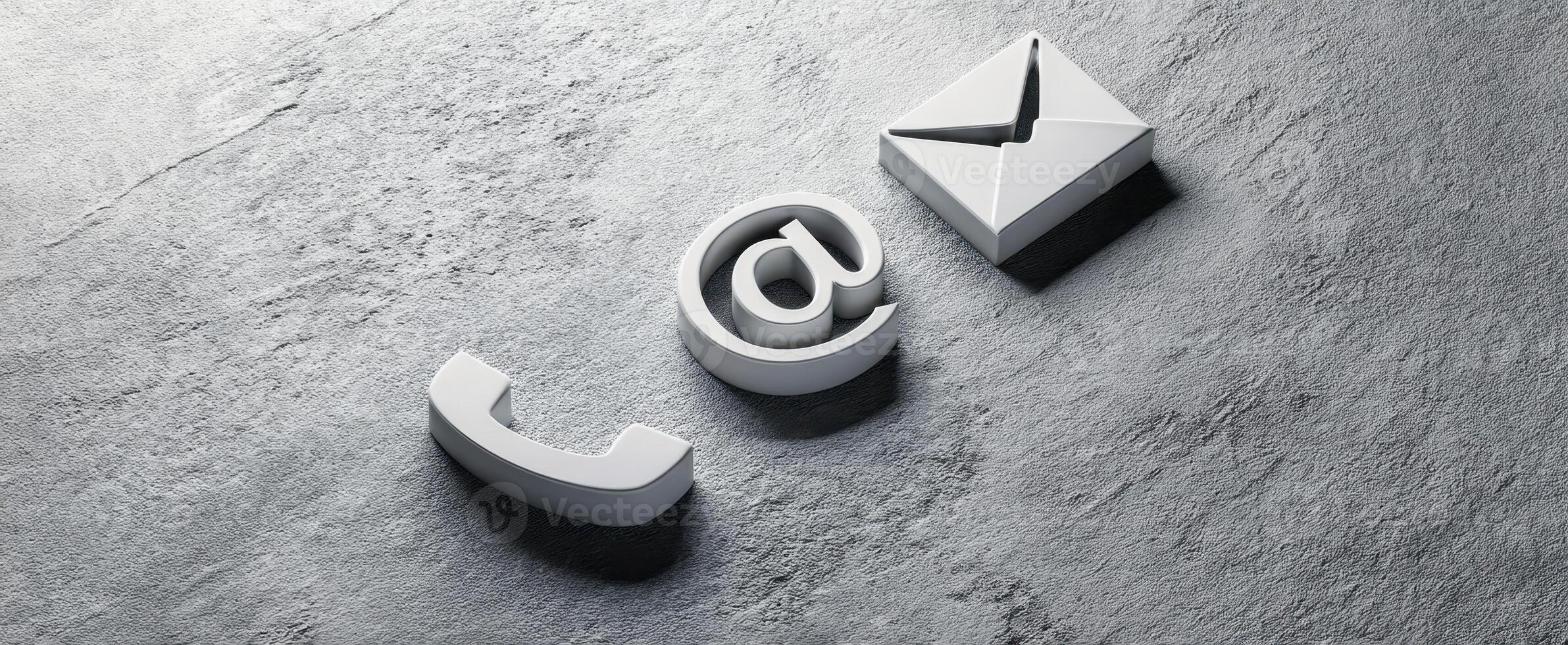 The digital communication symbols of phone, email, and at sign on a surface. photo