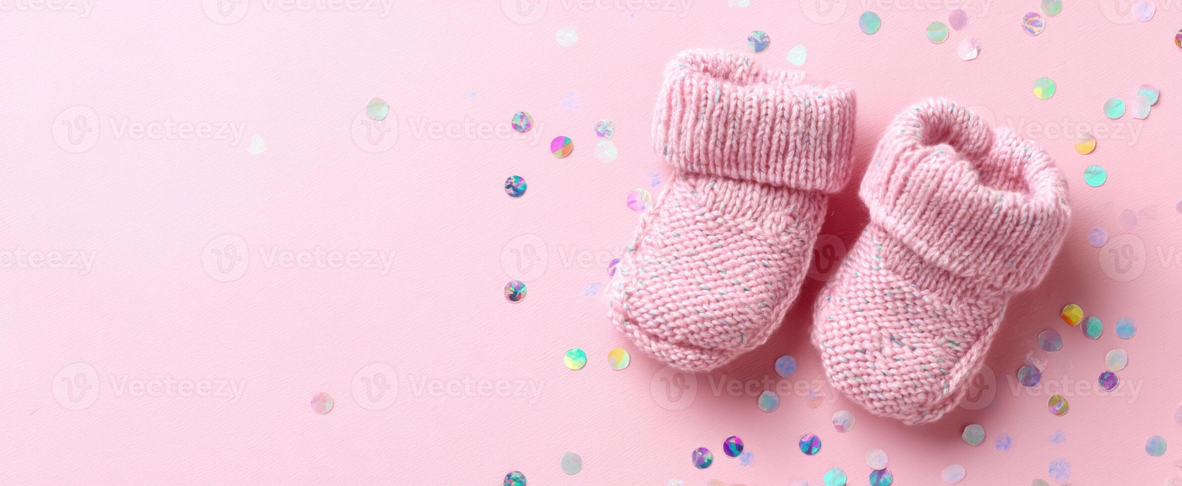 The adorable pink knitted booties adorned with sequins on a pastel background. photo