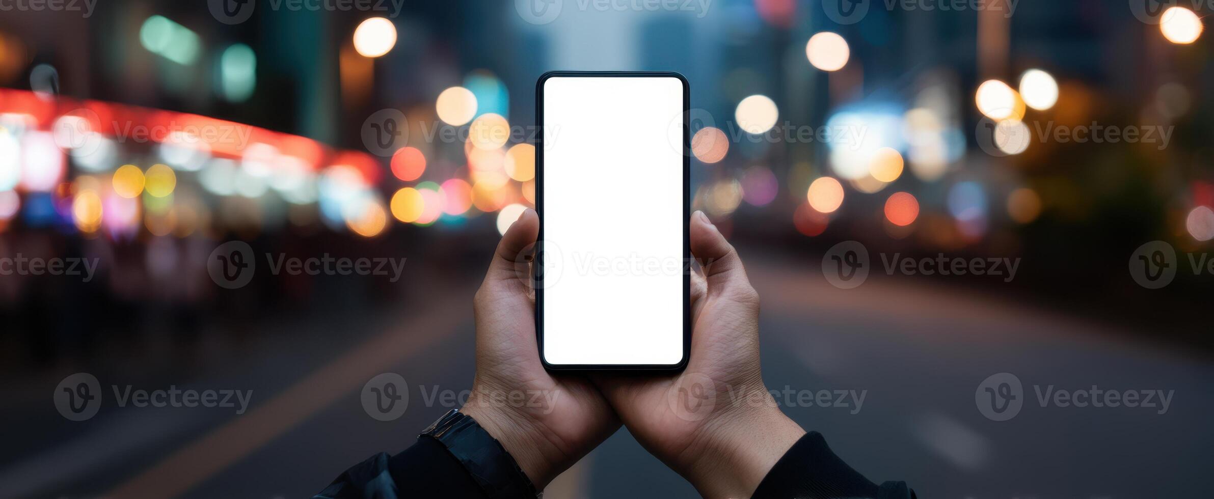 The smartphone held in hands against a blurred nighttime urban background. photo