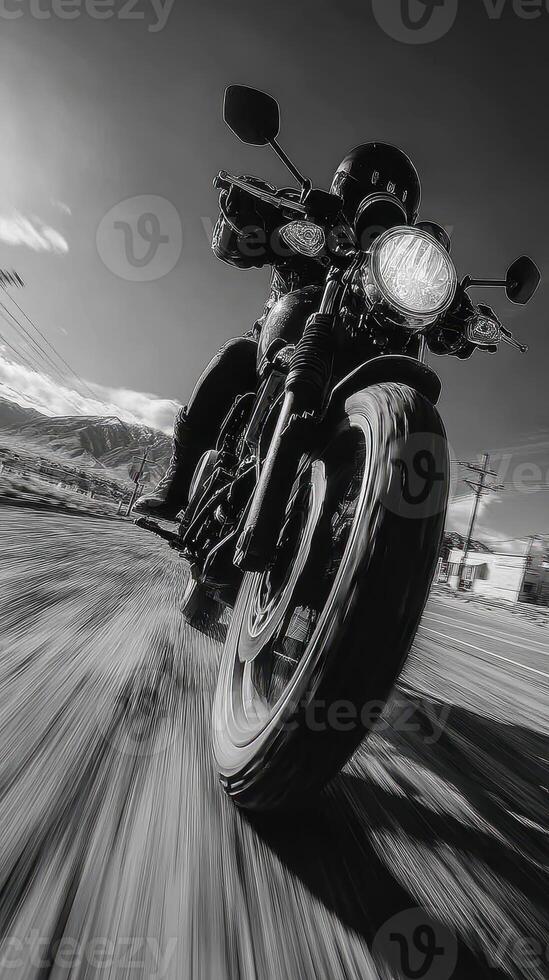 Motorcyclist riding fast along a rural road during a clear sunny day with mountains in the background photo