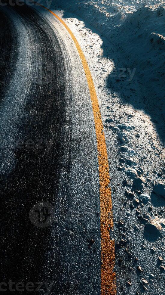 Winding road surrounded by snow at sunset near a mountain in winter photo