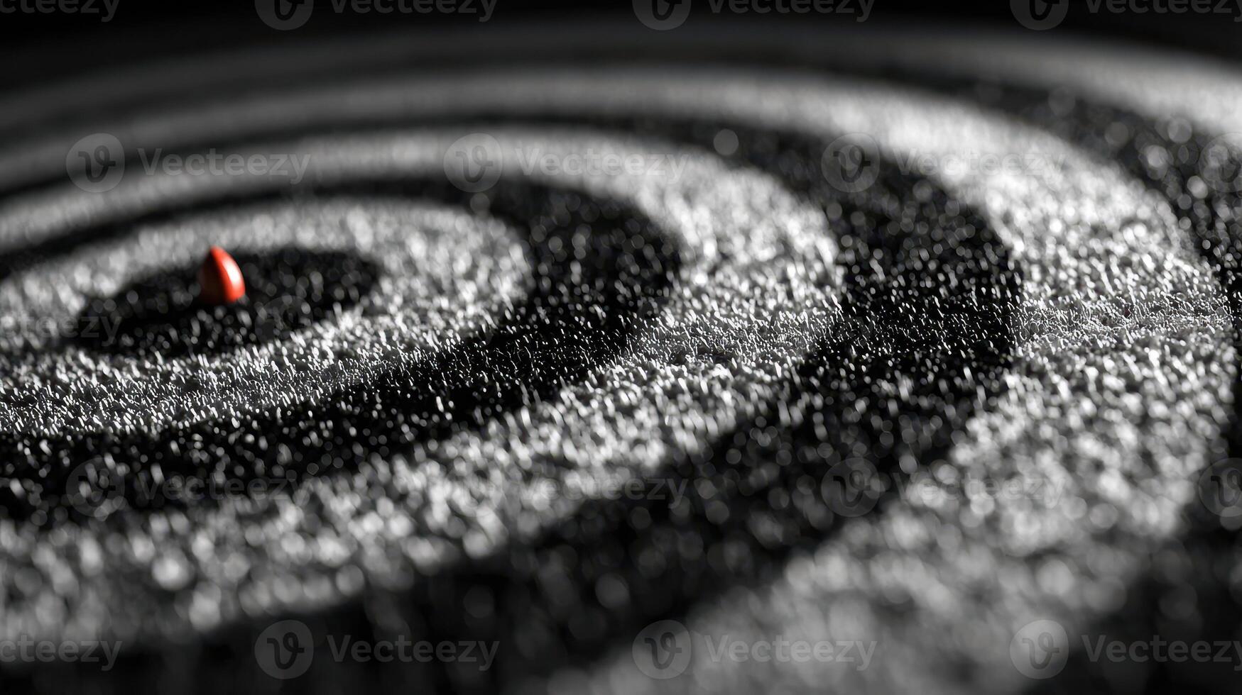 Concentric circles of fine salt with a single red object at the center create a striking visual contrast photo