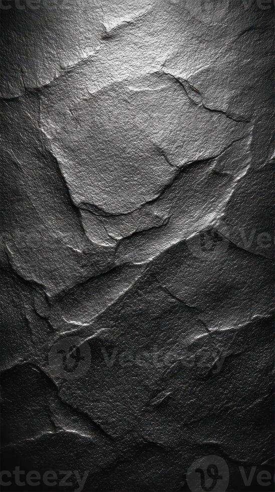 Textured black stone surface with distinct layers and shadows in natural lighting photo