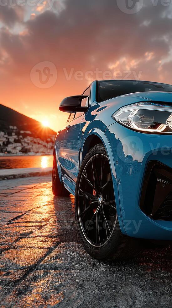 Modern blue SUV parked near the coastline during sunset, showcasing its sleek design and reflective surface against the vibrant sky photo