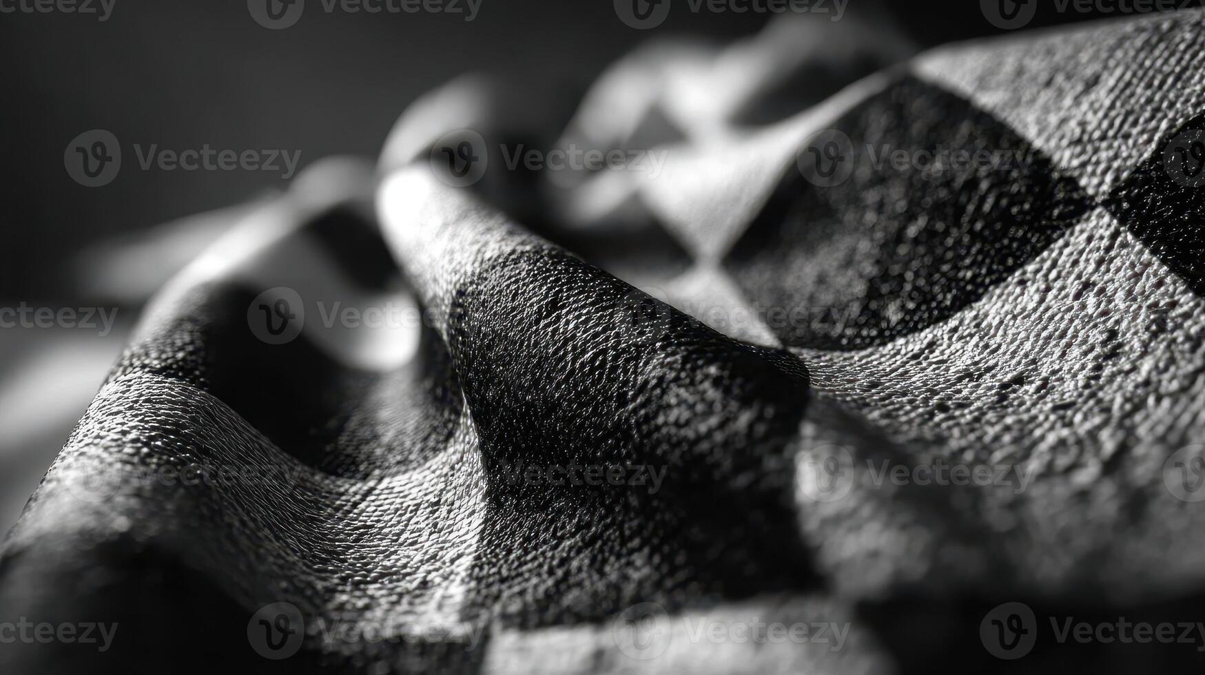 Textured black and white fabric with a checkered pattern displaying intricate folds and shadows in natural light photo