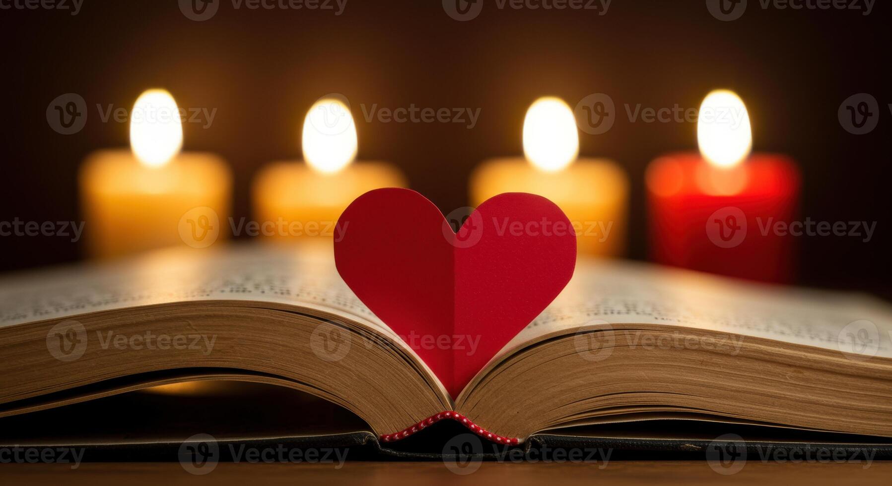 Open book with red heart bookmark and lit candles photo