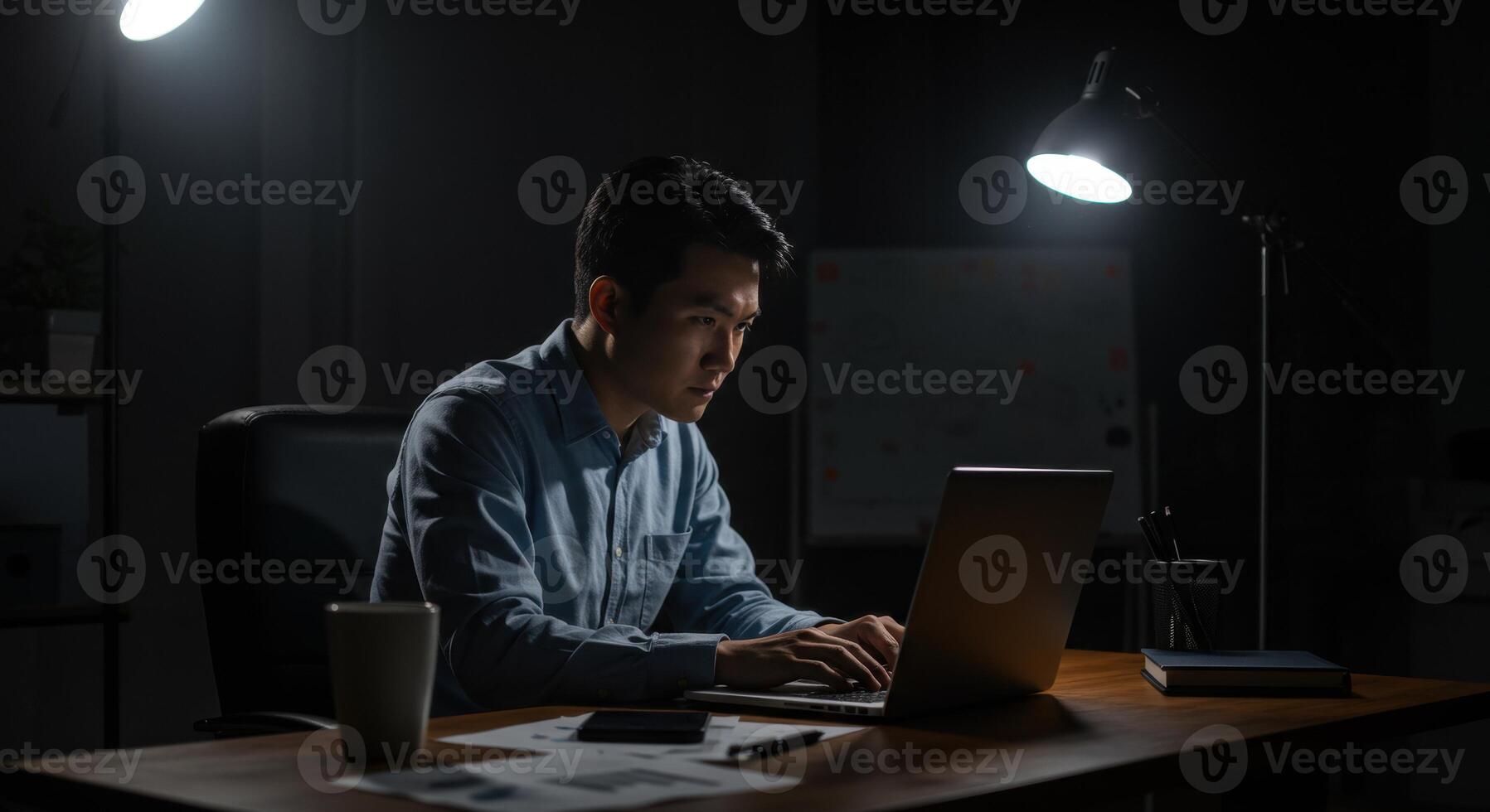 Asian man working on laptop late at night photo