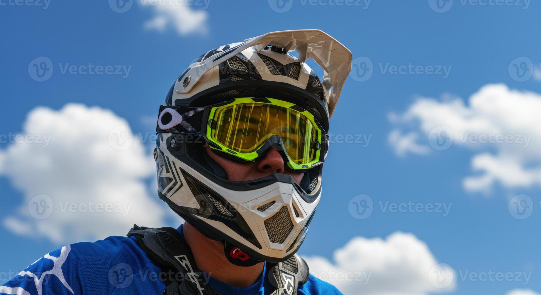 Close up of a motocross rider wearing helmet and goggles against blue sky photo