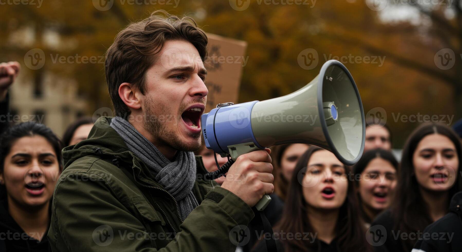 Male activist shouting into a megaphone leading a protest crowd photo