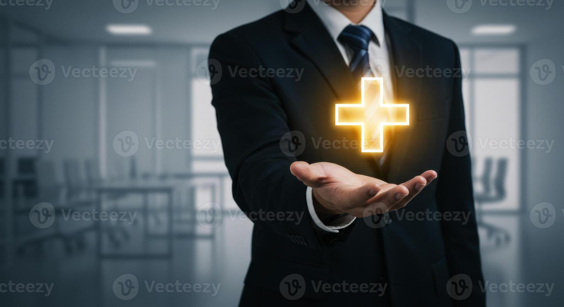 Businessman holding a glowing plus symbol in his hand representing health or positive concept photo