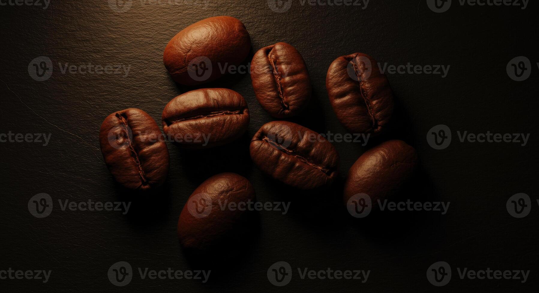 Roasted coffee beans scattered on a dark textured surface close up overhead view photo