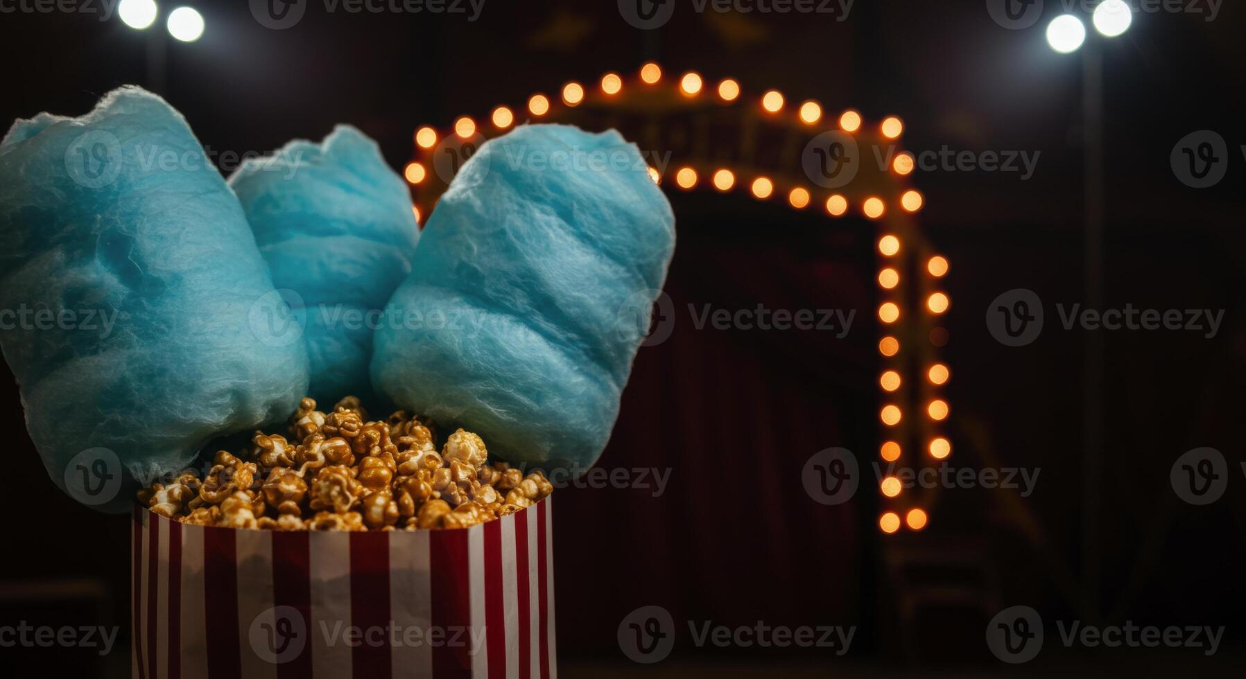 Striped bag filled with caramel popcorn and blue cotton candy at a circus photo