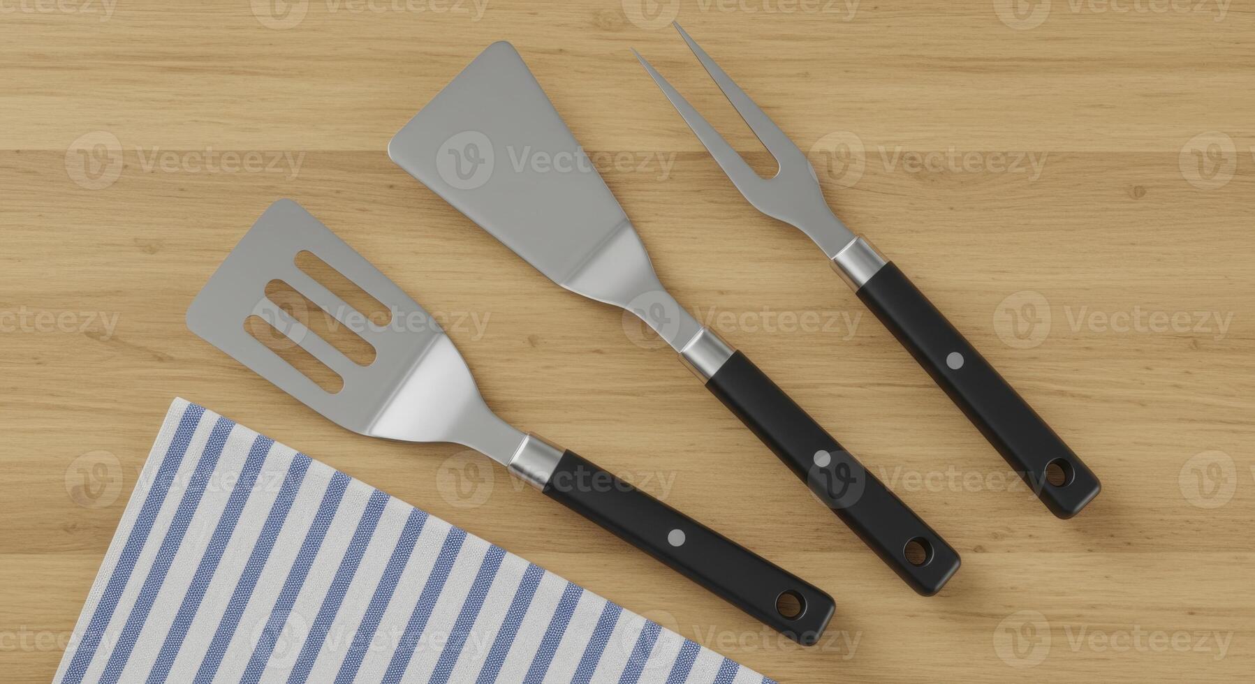 Metal barbecue tools including spatulas and meat fork on wooden surface photo
