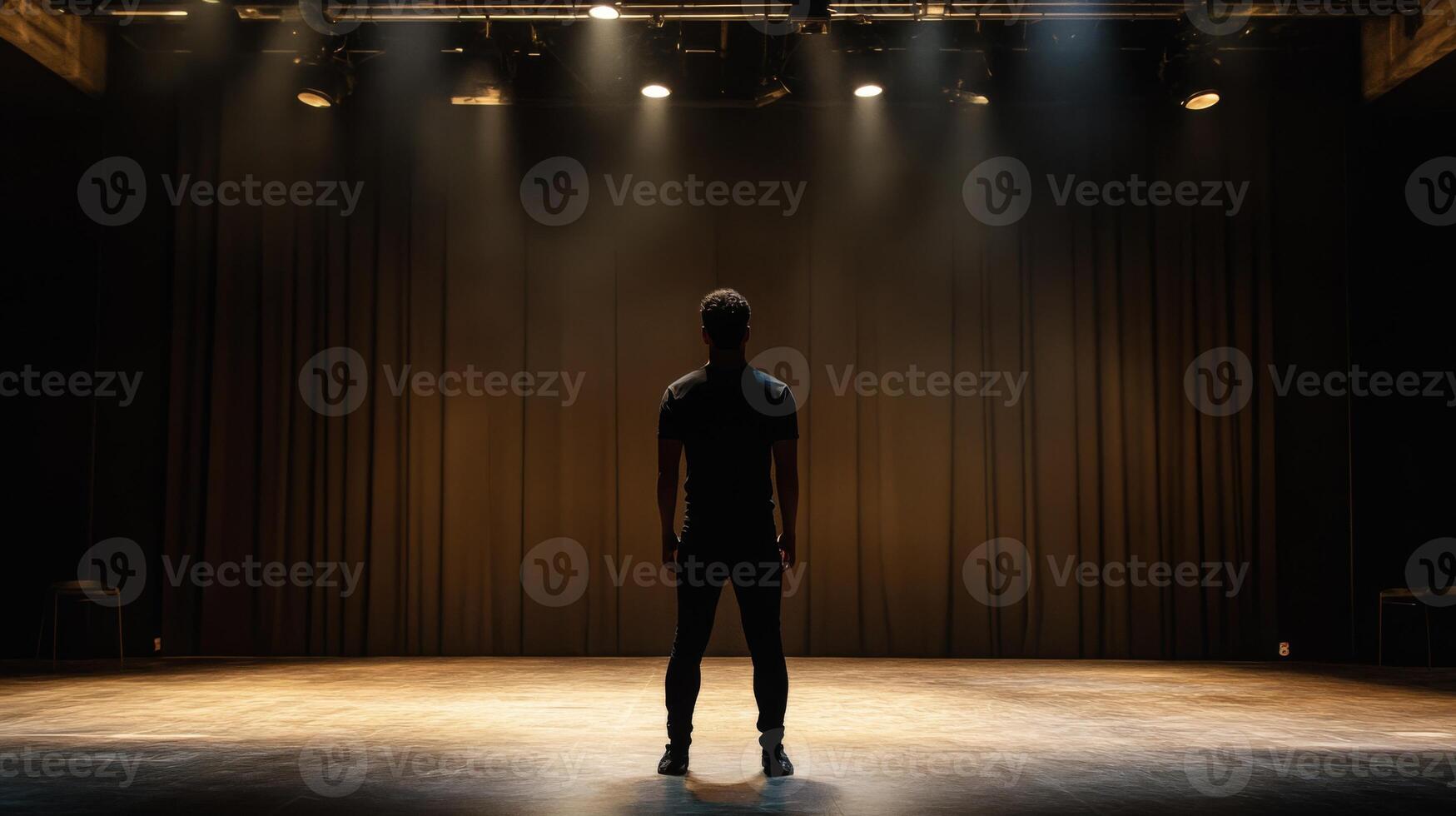 A Man Standing on a Stage in Front of a Dark Curtain photo