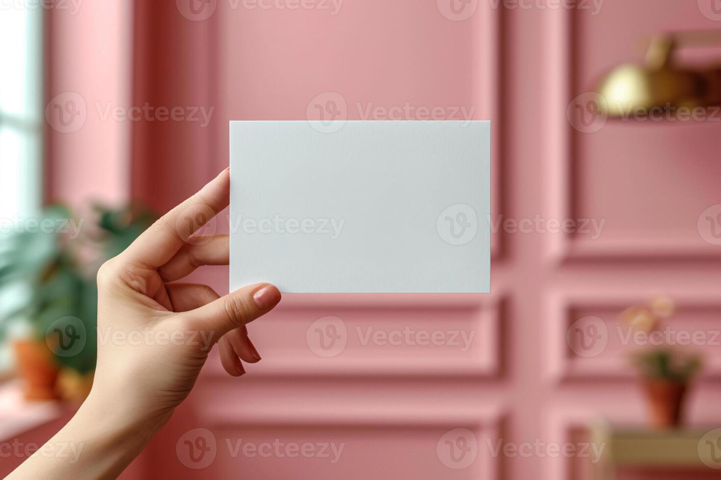 A person holding a blank card in front of a pink wall photo