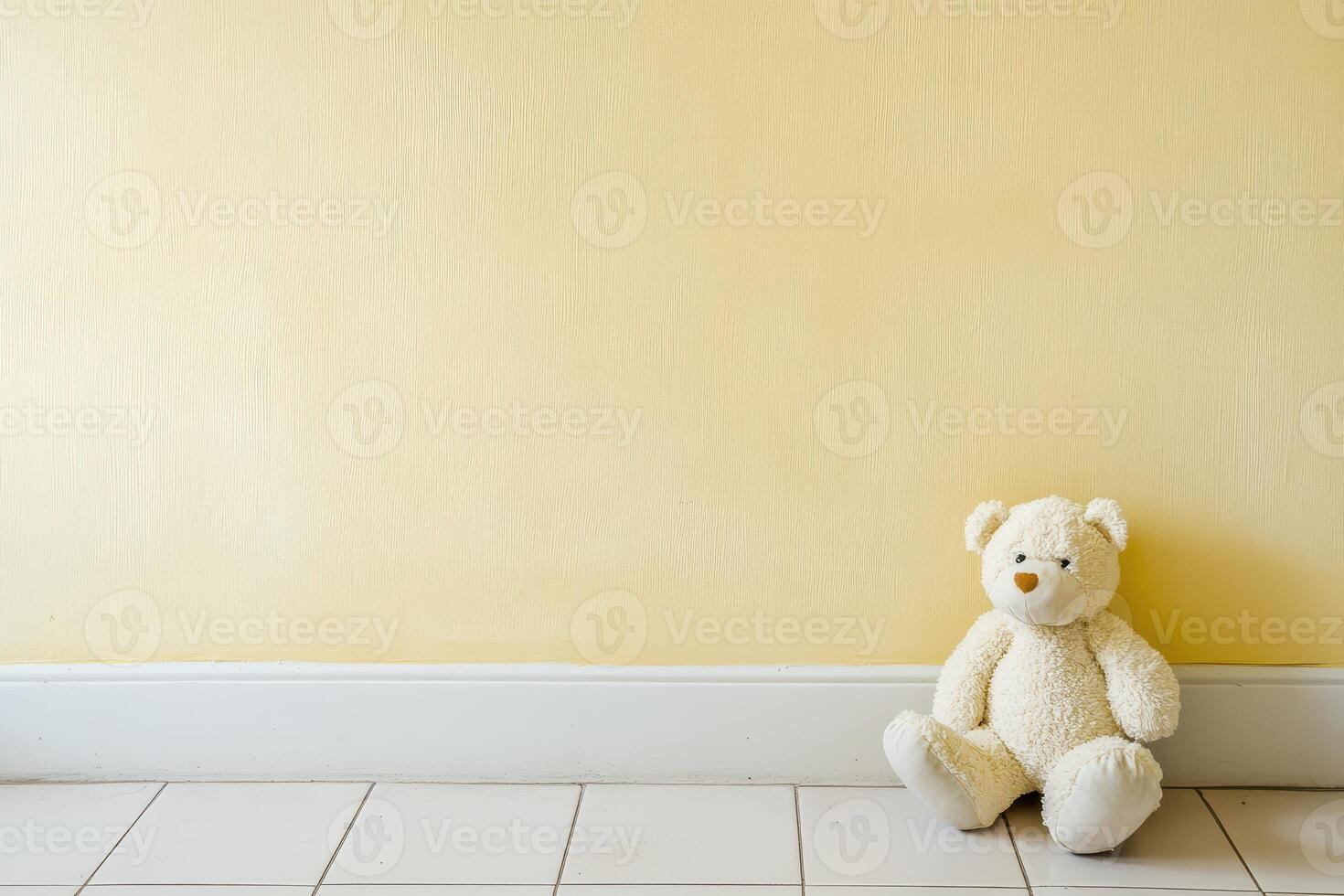 Teddy bear rests quietly against a yellow wall photo