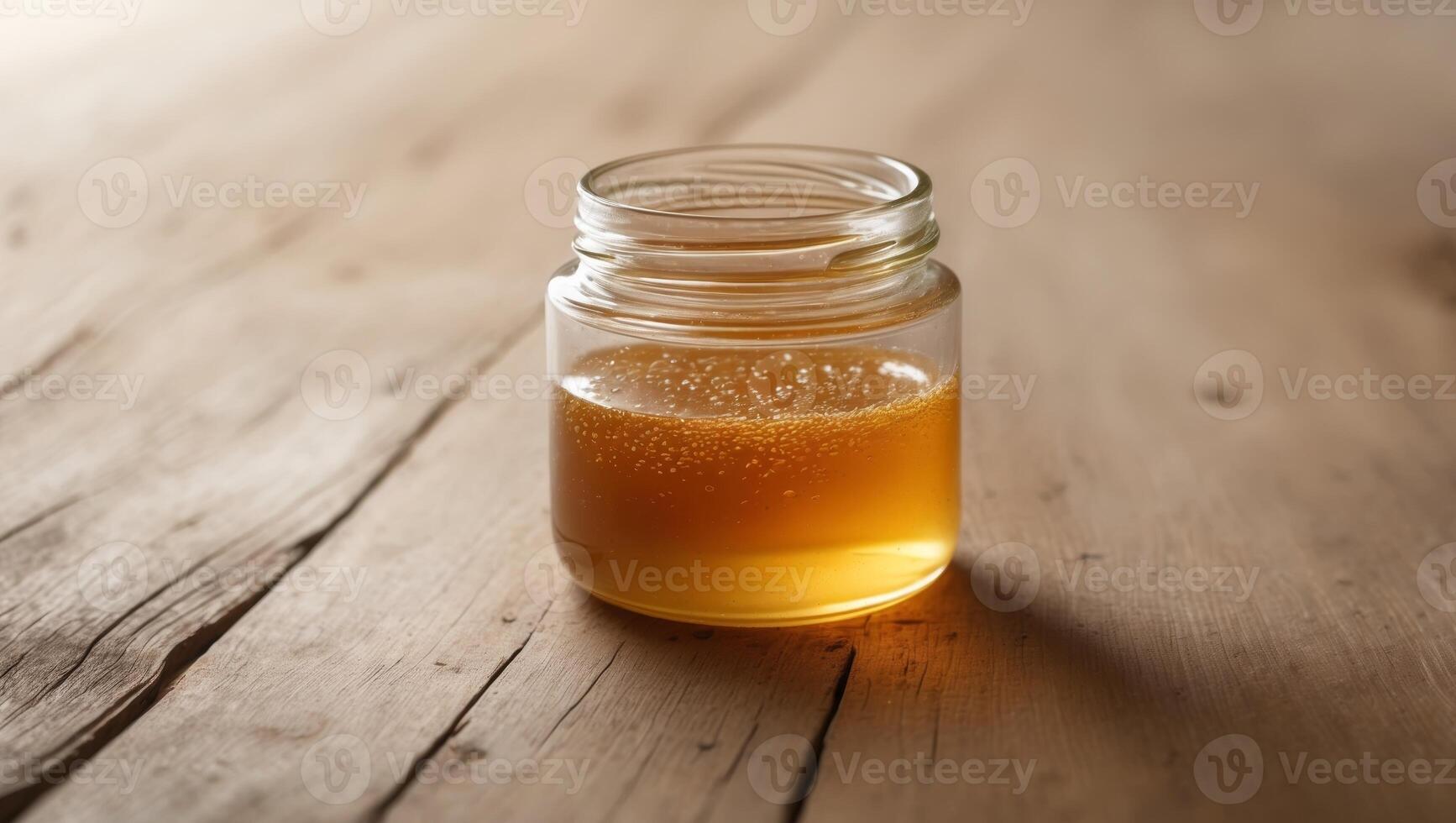 A glass jar filled with honey on a wooden table photo