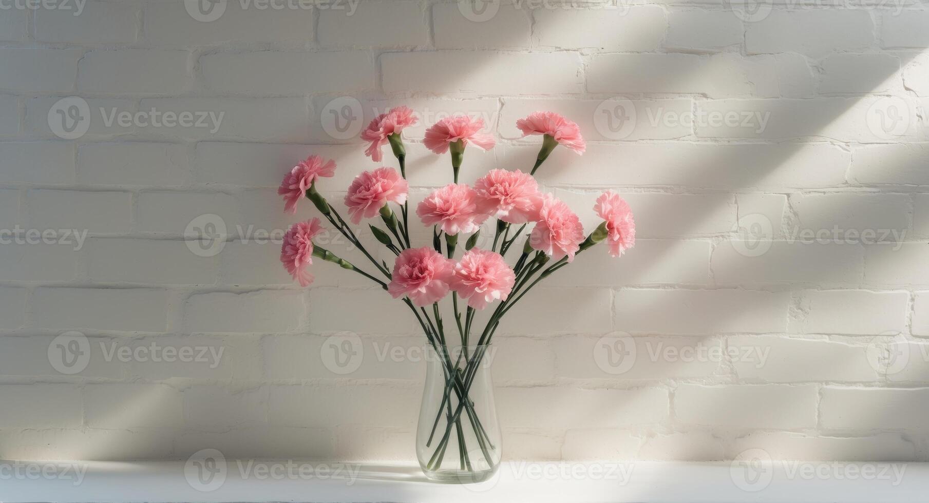Pink Carnations in a Glass Vase Against a White Brick Wall with Natural Light. photo