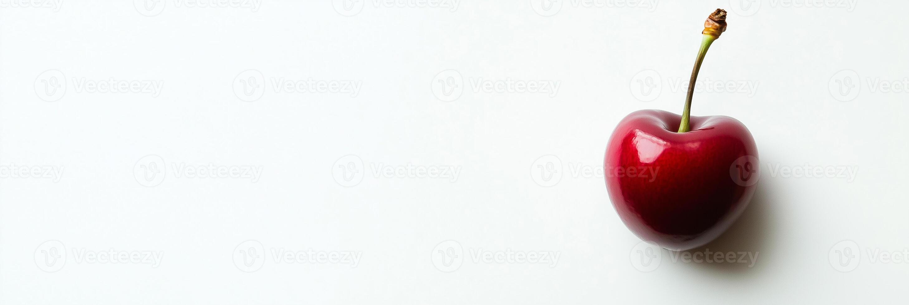 A cherry is shown on a white surface photo