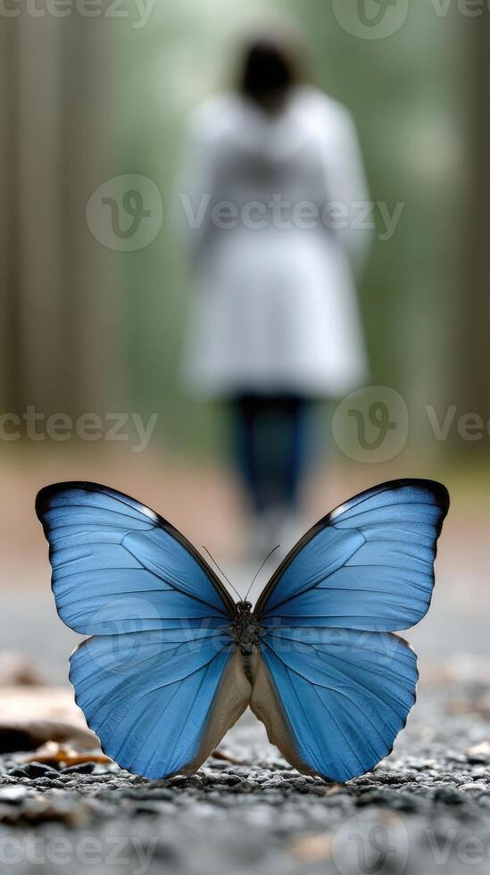 A blue butterfly is sitting on the ground next to a woman photo