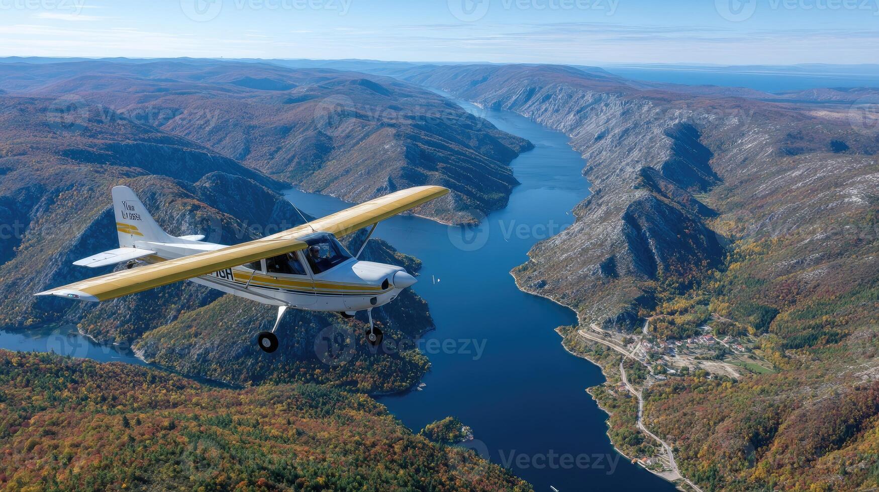 A small airplane flying over a river and mountains photo
