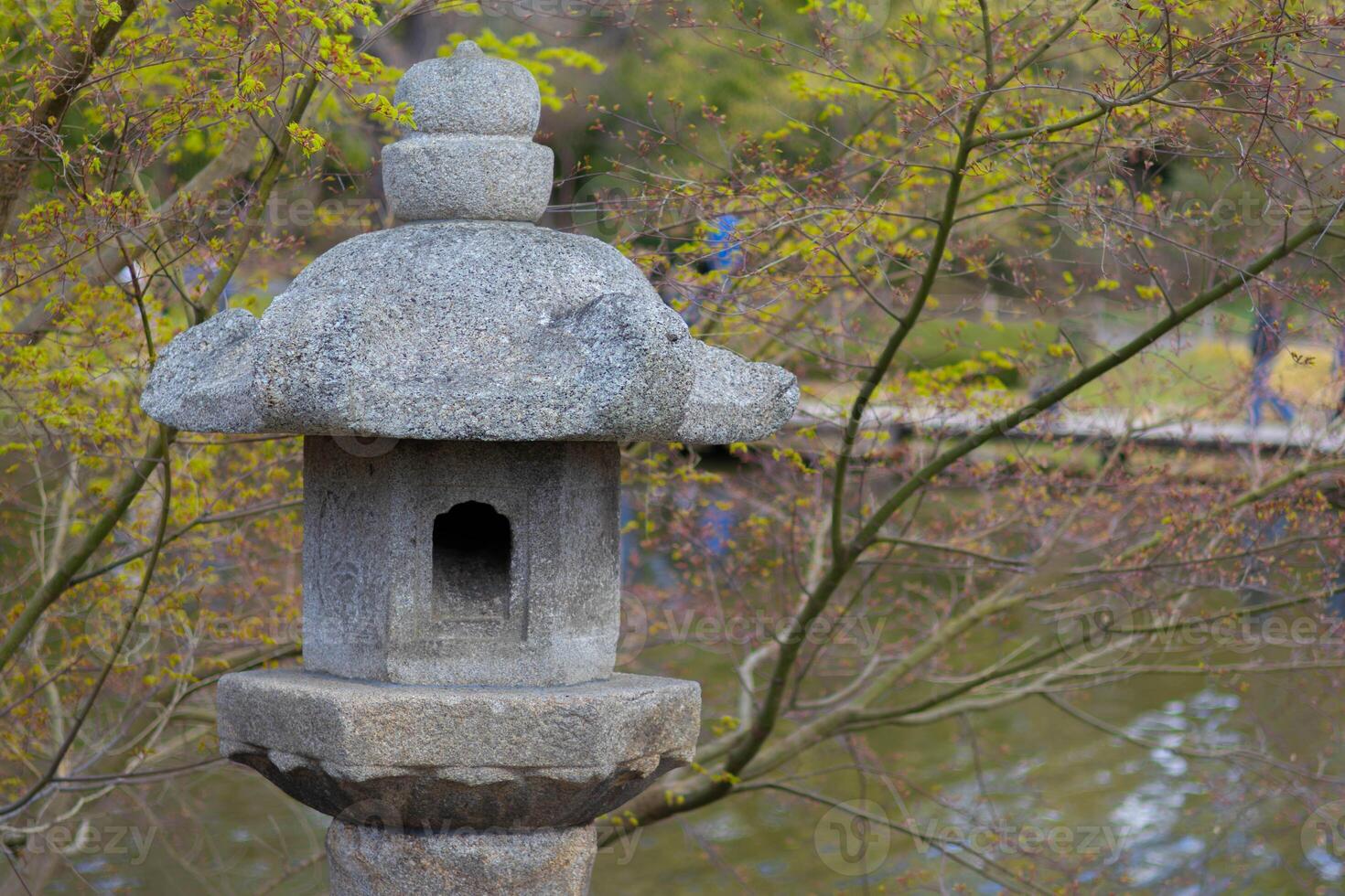 Stone lantern beside a pond in a serene Japanese garden setting photo