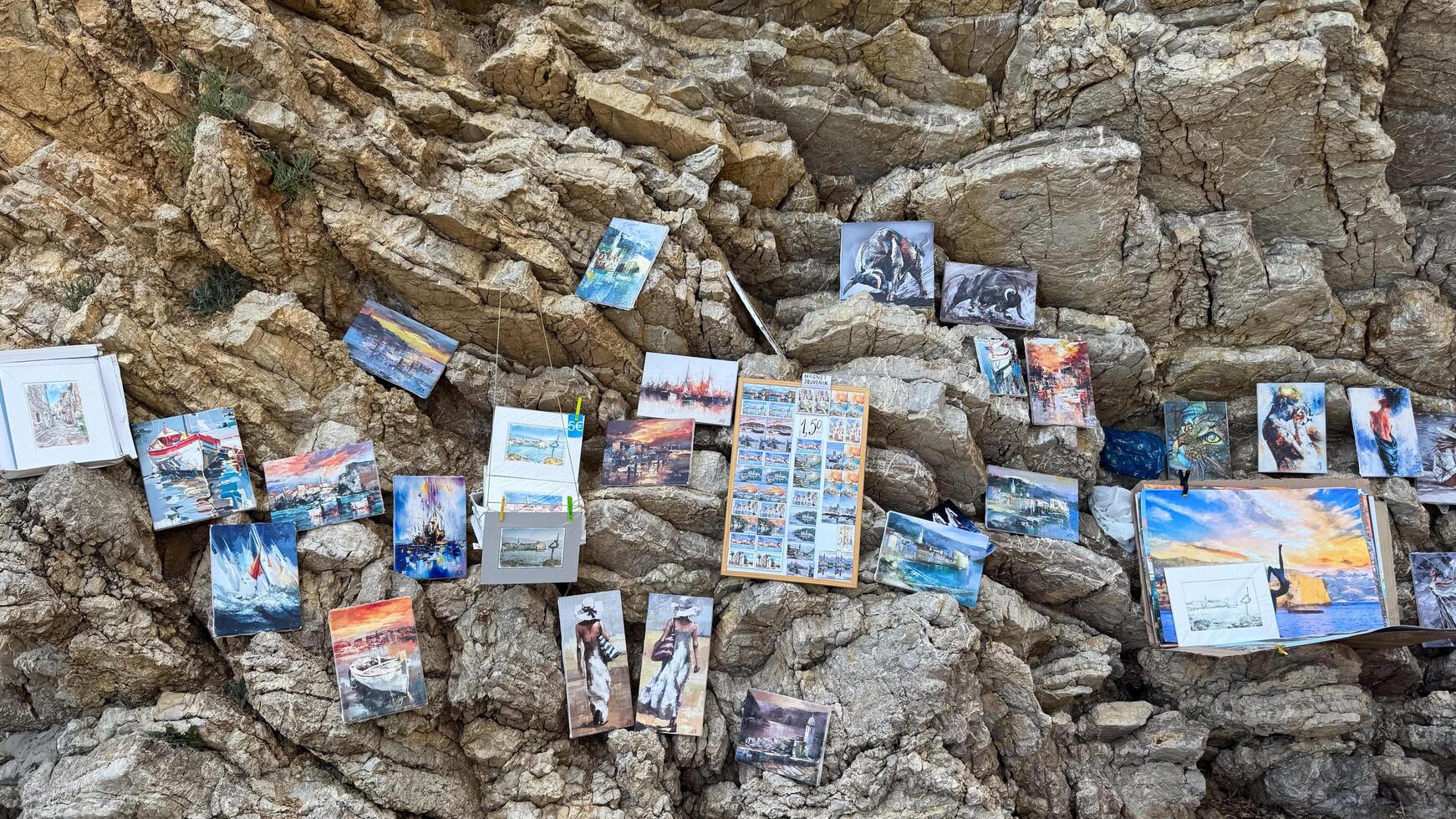 Budva, Montenegro - May 18, 2025. An art exhibition on a rocky cliff near Mogren Beach, displaying various paintings and scenic views. photo