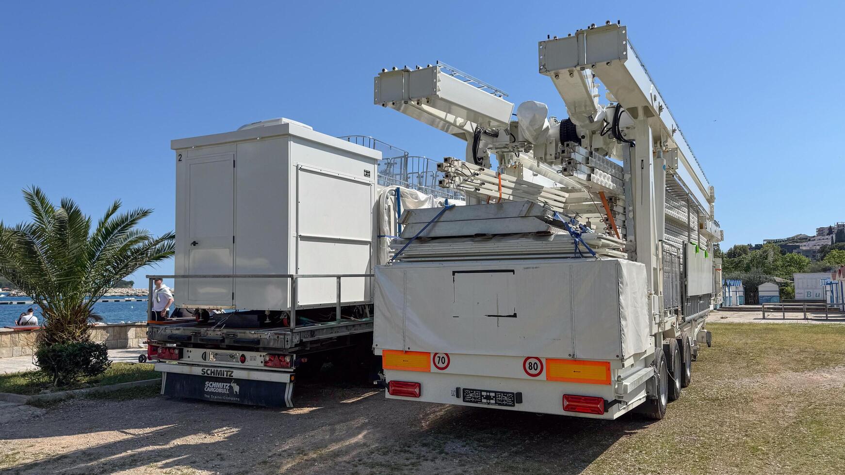Budva, Montenegro - May 18, 2025. Ferris wheel cabins are folded on truck beside scenic waterfront view photo