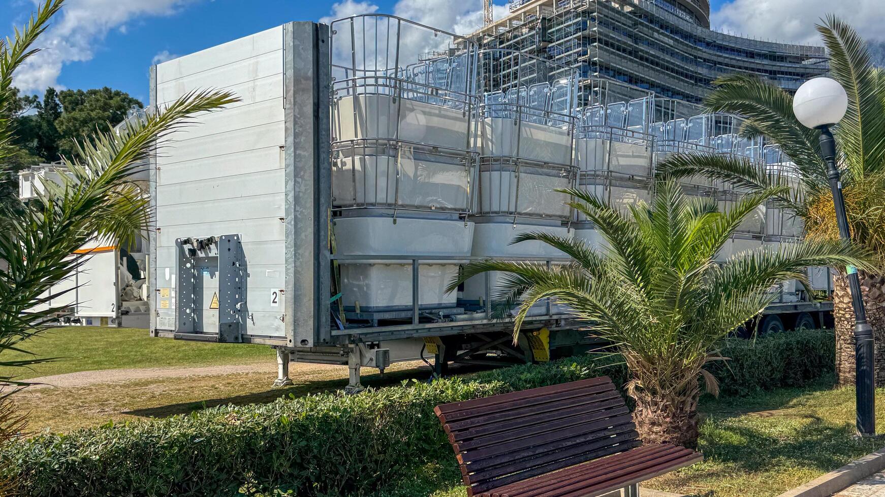 Budva, Montenegro - May 18, 2025. Transport trailer carrying folded ferris wheel cabins surrounded by palm trees photo