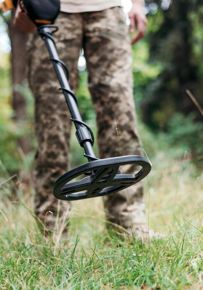A military sapper with a metal detector in the field. A Ukrainian explosive technician carries out demining work. photo
