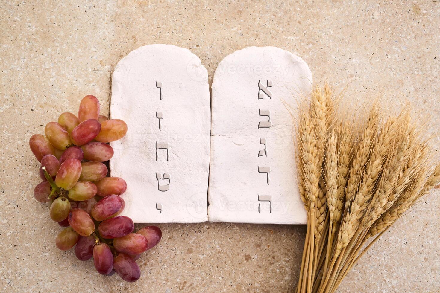 Happy Shavuot concept. Two Stones with Ten Commandments in Ancient Hebrew, Grains, milk and cheese photo