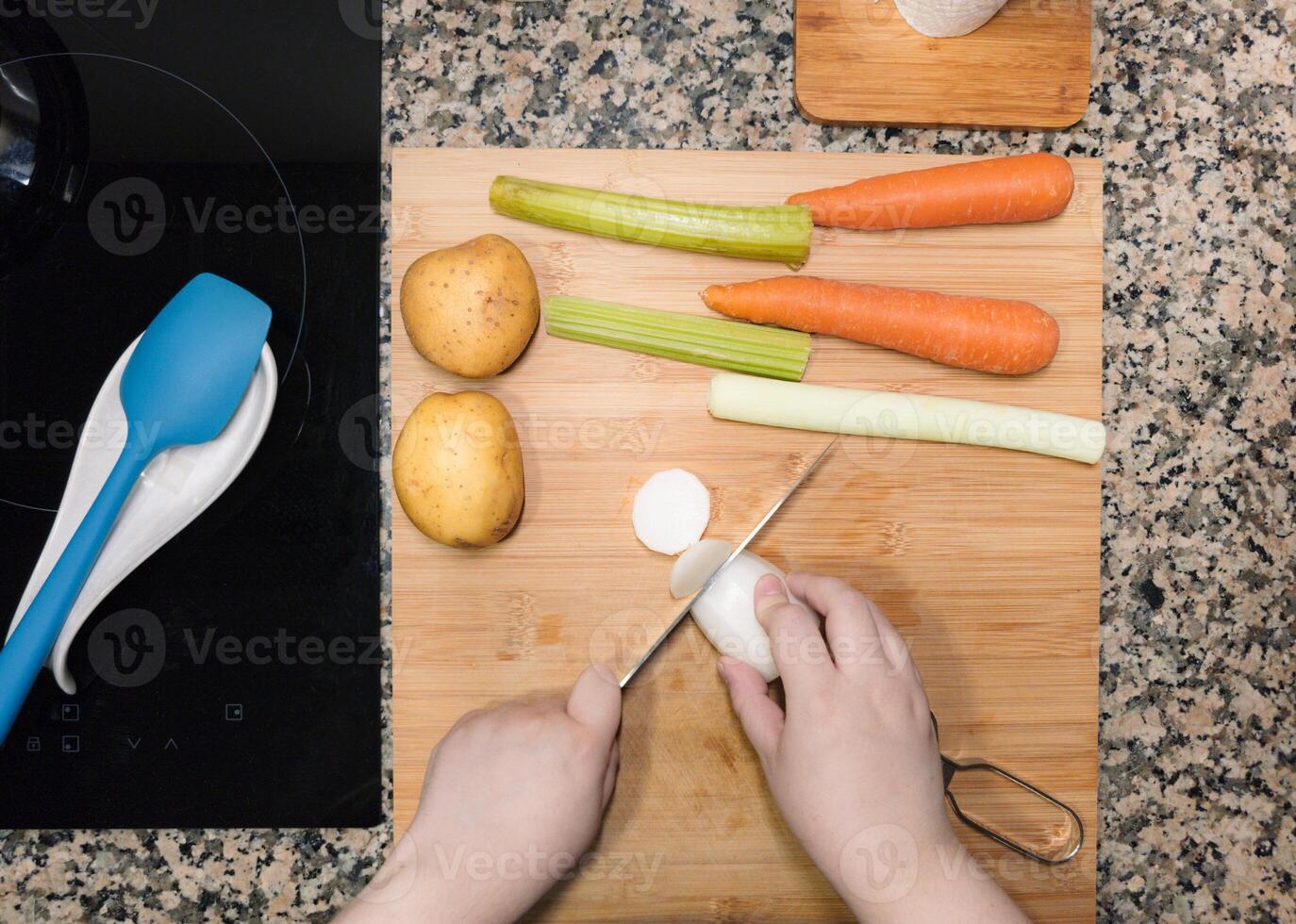 High angle of view of woman hands chopping a turnip against a wood cutting board at home kitchen. photo