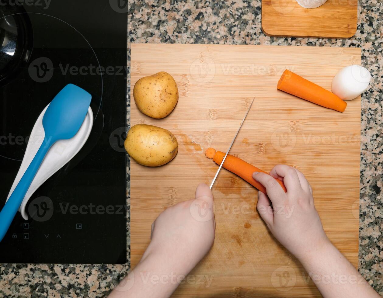 High view of chefs hands preparing and chopping vegetables. Kitchen scenery. Cooking recipe with ingredients around. Home made plate. photo