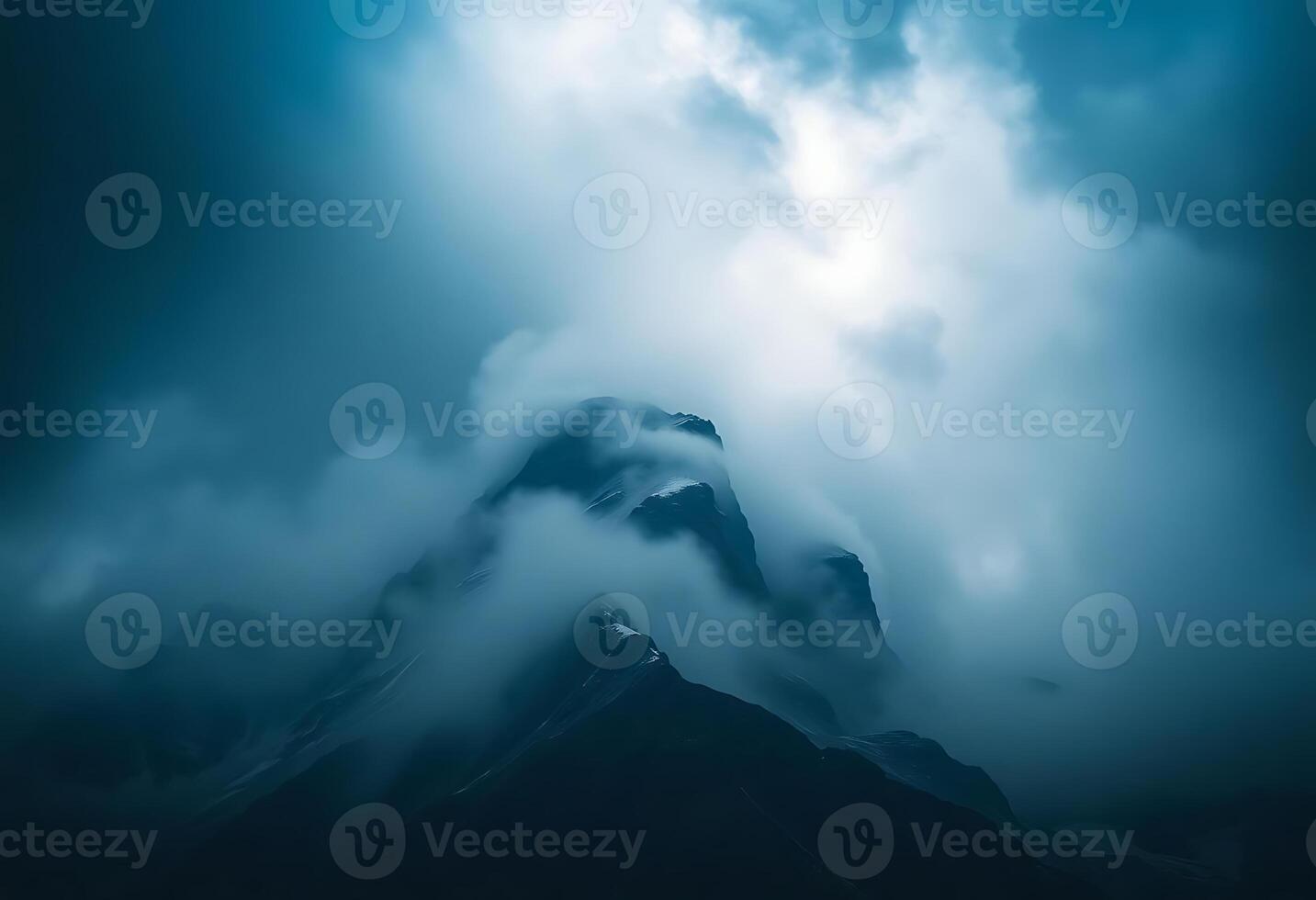 very tall mountain covered in clouds under a blue sky photo