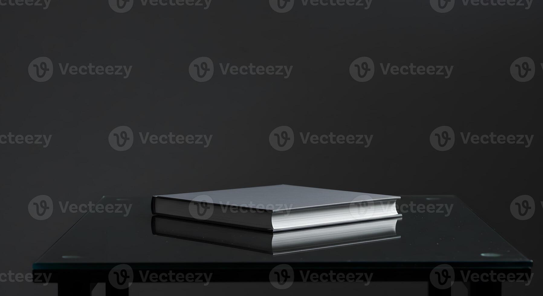 A book on a glass table in front of a black background photo
