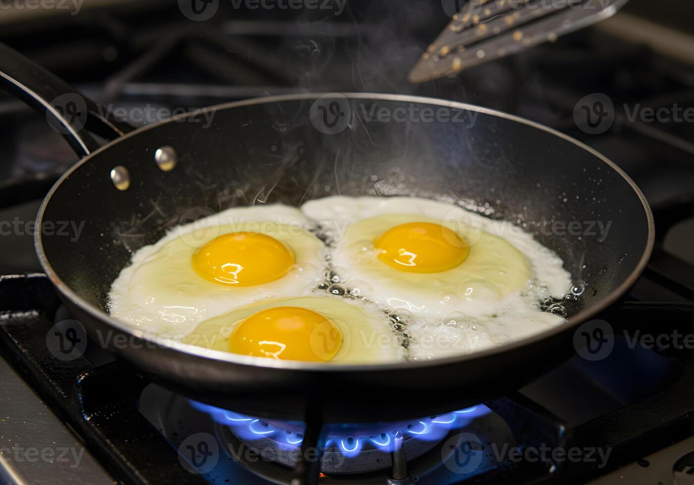 Three eggs are being cooked in a frying pan photo