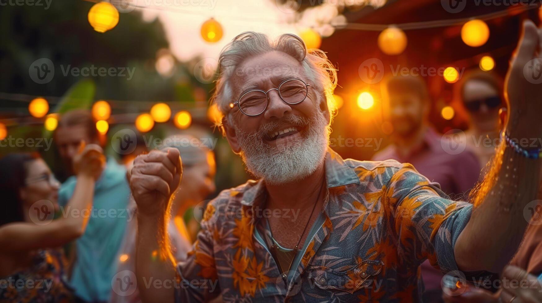 Joyful senior man dances and laughs with friends at a backyard party with string lights. photo